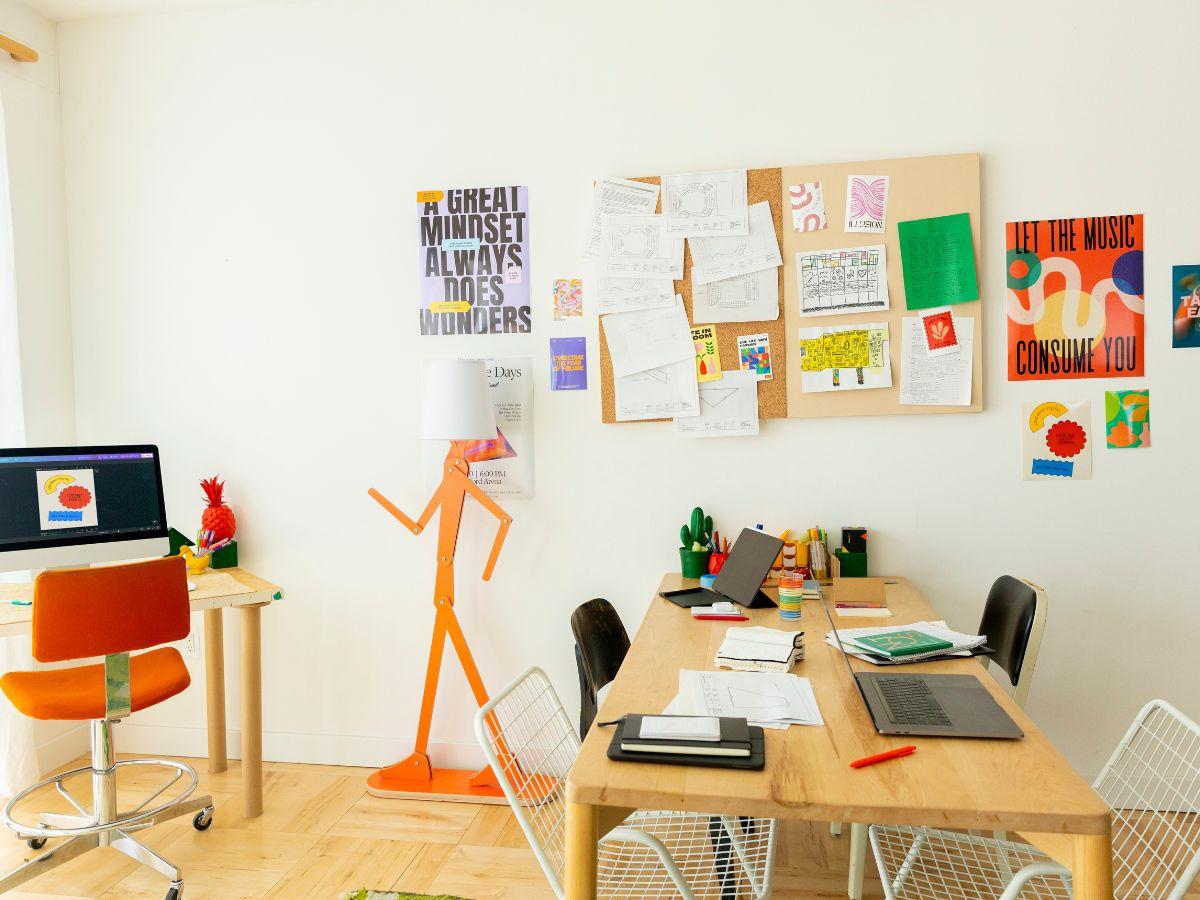 Estudio creativo de marketing con escritorio, laptop y pósteres de diseño en la pared