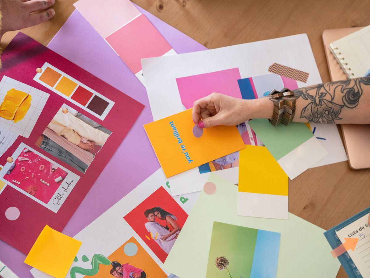 Manos organizando muestras de color y piezas gráficas sobre una mesa de diseño