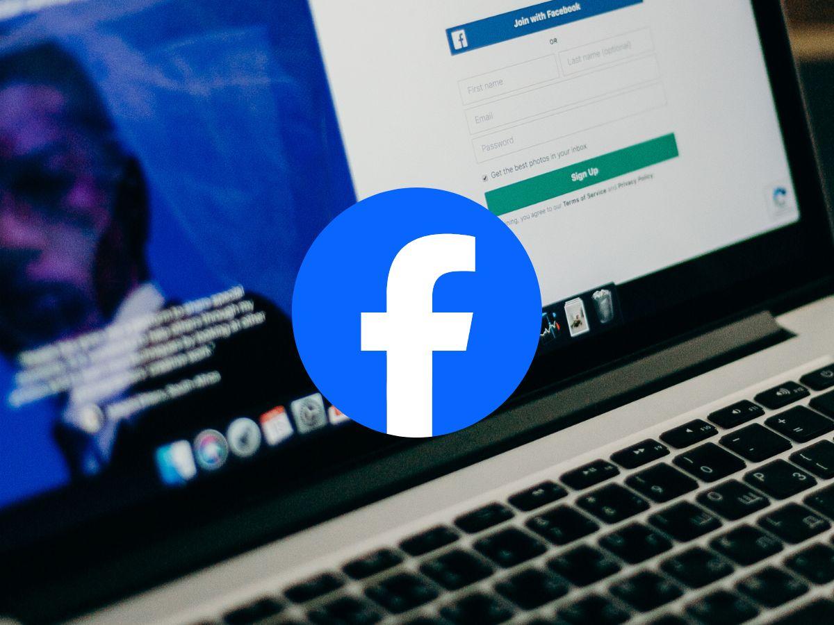 Laptop con Facebook en pantalla y el logotipo de Facebook en primer plano